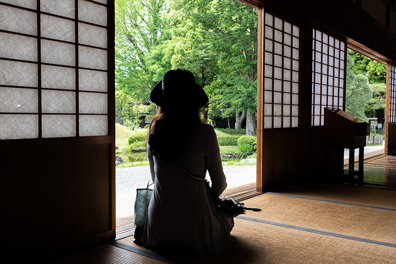 縁側から庭園を眺める妻